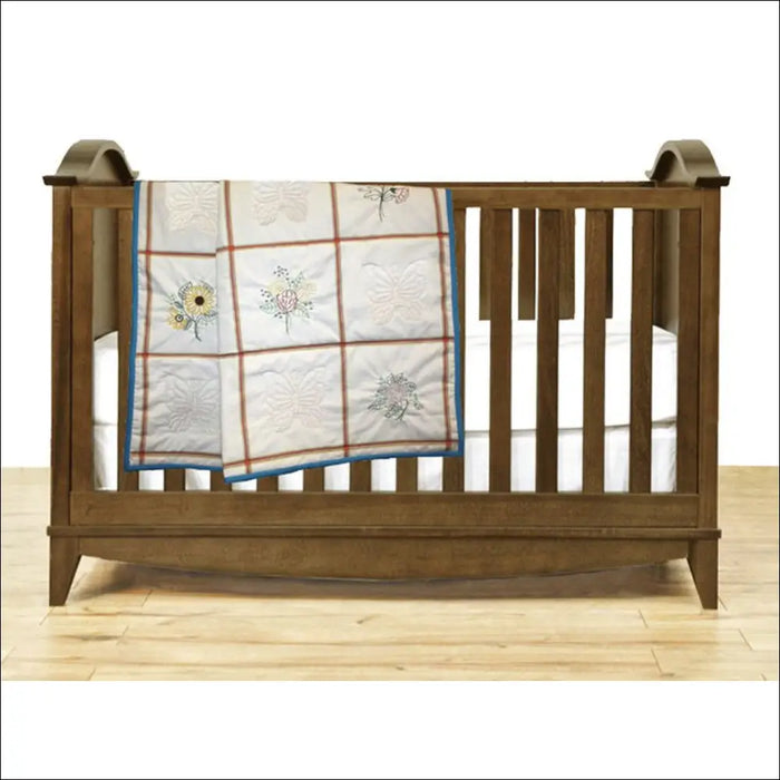 Wooden baby crib adorned with Aunt Martha’s Quilting Fabric in Multi Stripe Print