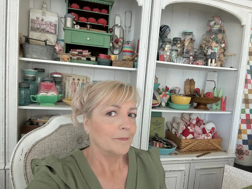 White corner cabinet filled with vintage kitchenware and collectibles.